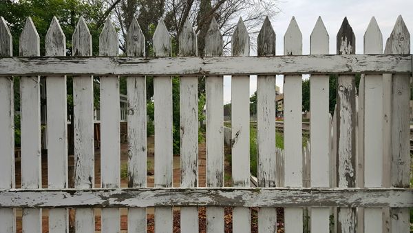 image of a weather-worn white picket fence on an overcast day