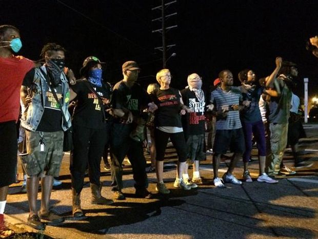 image of seven black women and men, one white woman, and one white man linking arms in anticipation of police pressure