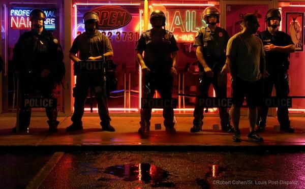 image of police lined up in front of a storefront in Ferguson on Saturday night
