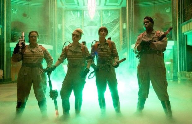 image of the four women in their Ghostbusters uniforms, holding blasters and surrounded by green mist