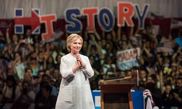 image of Hillary Clinton at her victory address on Tuesday, with a giant sign reading HISTORY behind her, and a cheering crowd, one of whose members is holding a sign reading MADAM PRESIDENT