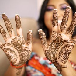 image of an Indian woman holding up her hands, which have been decorated with henna tattoos