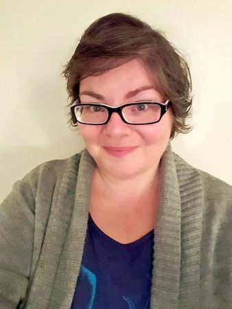 image of me wearing a blue t-shirt, grey cardigan, black-framed glasses, and light make-up