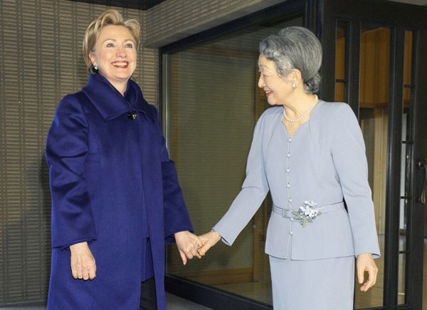 image of Hillary Clinton standing and holding hands with Japan's Empress Michiko, a thin Japanese woman