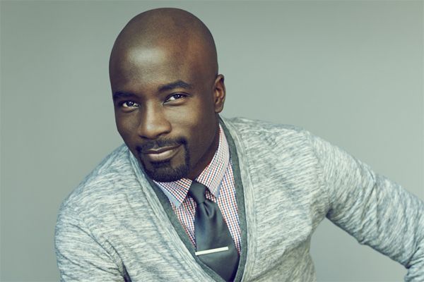 image of Mike Colter, a young, thin, black man with a shaved head and a van dyke
