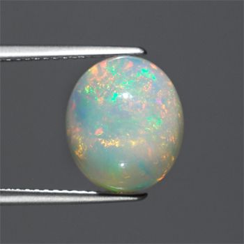 image of tweezers holding a smooth, round piece of opal in front of a grey background