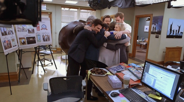 image of the Parks & Rec gang in the Parks Dept. office, sharing a group hug