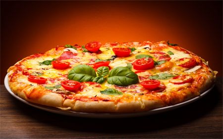 image of a pizza with basil and tomatoes