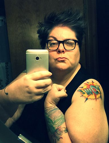 image of me in my mirror, making a faux-tough face and showing off my upper right arm with POW! tattoo