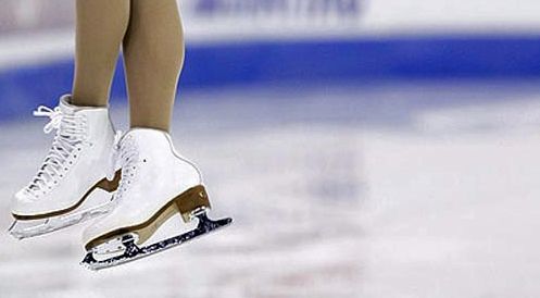 image of a woman's feet in figure skates, as she jumps above the ice