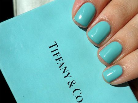 image of a what appears to be white woman's hand holding a Tiffany & Co. blue gift box, with nails painted to match