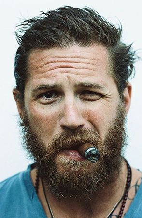 image of actor Tom Hardy, looking very scruffy and smoking a cigar