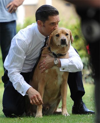 image of Tom Hardy crouching behind Woodstock, giving him a kiss on the head