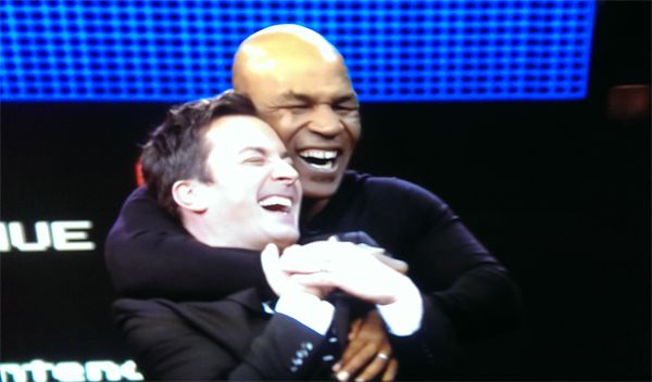 image of Jimmy Fallon being hugged from behind by Mike Tyson; they are both smiling and laughing