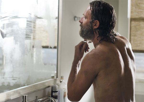 image of Rick Grimes standing at a steamy mirror, shaving off his beard
