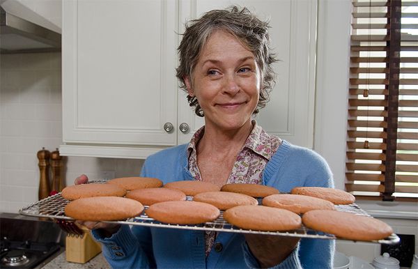 screen cap from The Walking Dead in which Carol is standing in a kitchen holding a baking sheet full of cookies straight from the oven