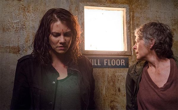 screen cap from The Walking Dead of Maggie and Carol looking frightened, standing next to a door labeled 'Kill Floor'
