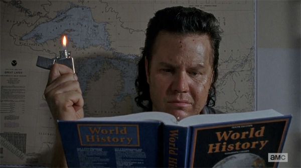 screen cap from The Walking Dead of Dr. Mulletsworth reading a World History textbook by Zippo light