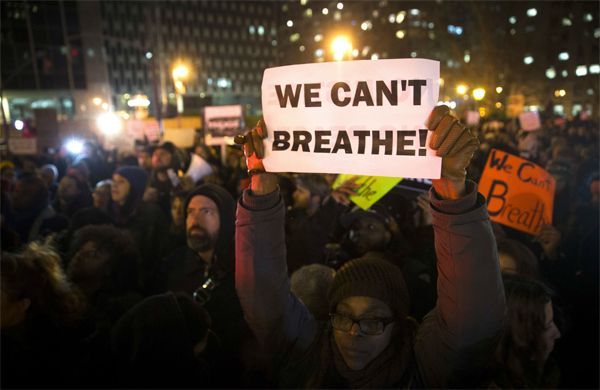 image of protestors in NYC; a black woman holds up a handwritten sign reading WE CAN'T BREATHE