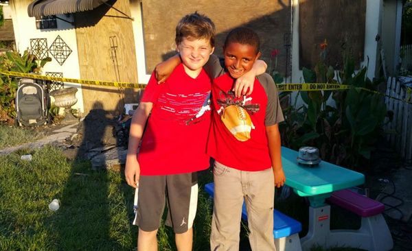 image of a young white boy and a young black boy standing with their arms around each other's shoulders, smiling