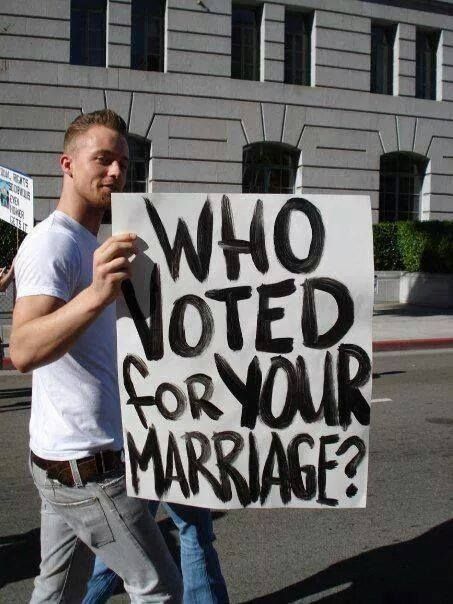 image of a thin, young, white man walking holding a handwritten sign reading: 'Who voted for your marriage?'