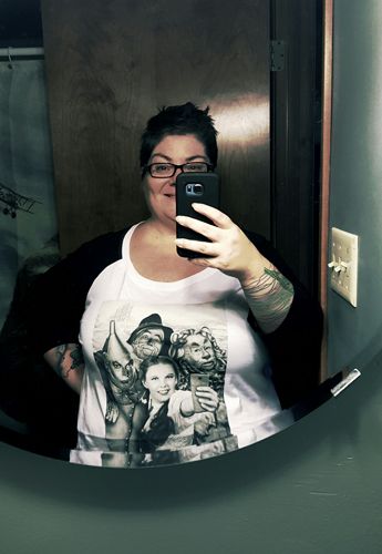 image of me standing in my bathroom, taking a selfie in the mirror, wearing a t-shirt with the cast of Wizard of Oz of whom Dorothy is taking a selfie