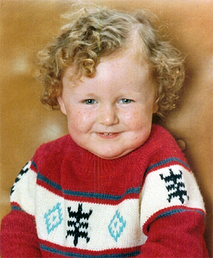 image of Iain as a baby, with a tumble of curly red hair, freckly fat cheeks, and wearing a winter snowflake sweater
