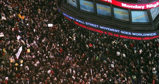 image of crowd protesting in Times Square, beside news ticker featuring a headline about the movement