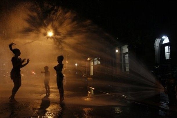 silhouettes of children playing in a spraying hydrant at nighttime