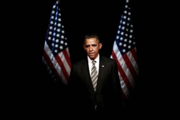 image of President Obama flanked by two American flags, giving him the appearance of having red-white-n-blue wings: 'President Barack Obama pauses before shaking hands at a campaign event, Thursday, Jan. 19, 2012, at the Apollo Theatre in the Harlem neighborhood of New York. [AP Photo]'