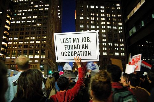 image of a protester holding up a sign reading 'Lost My Job, Found an Occupation'