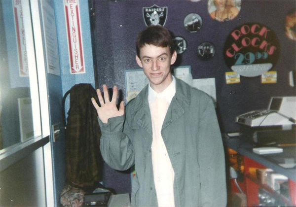 image of young Deeks standing and waving at the camera with slightly raised eyebrow
