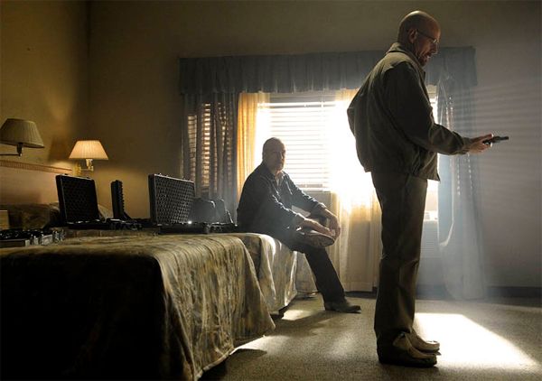 image of Walt holding a gun in a hotel room during a meeing with a small arms dealer