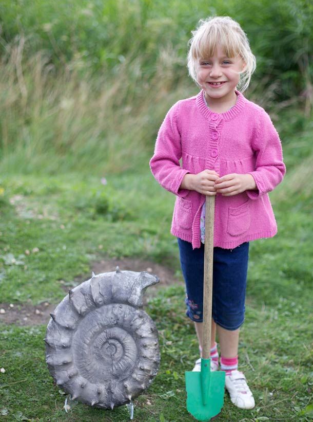 6-year-old Emily Baldry stands beside a 160 million-year-old ammonite fossil
