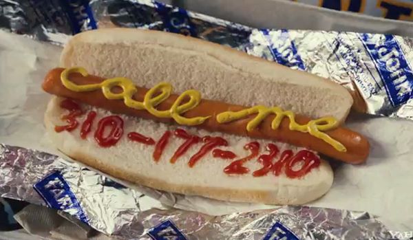 screen cap of hotdog with 'call me' and a phone number written in ketchup and mustand
