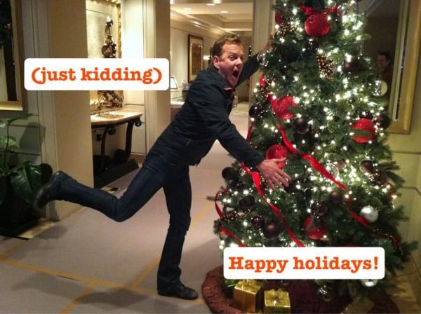 image of actor Kiefer Sutherland pretending to jump into a Christmas tree, labeled '(Just Kidding) Happy Holidays!'