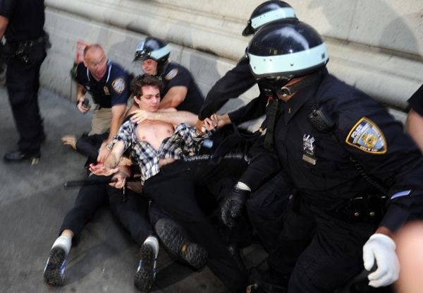 image of demonstrator being roughly pulled to the ground by several police officers