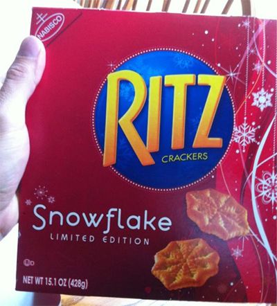 Paul F. Tompkins' hand holding a box of holiday-themed 'Snowflake' Limited Edition Ritz Crackers