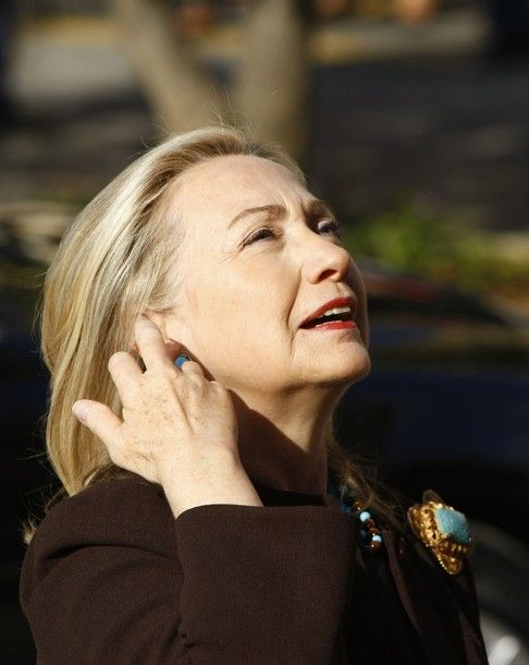 image of Secretary Clinton standing in the sunshine, smoothing back her hair