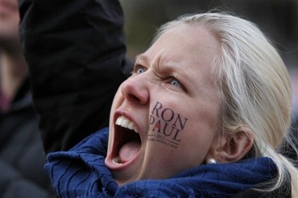 image of young blond woman cheering passionately with a Ron Paul decal on her face