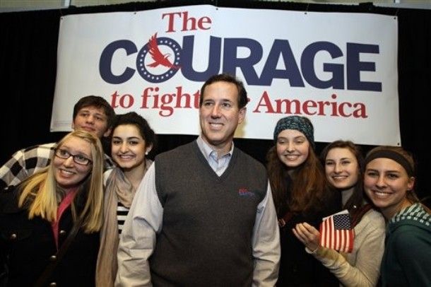 image of Rick Santorum standing with some young people in front of a huge sign reading 'The Courage to Fight for America' at a campaign event