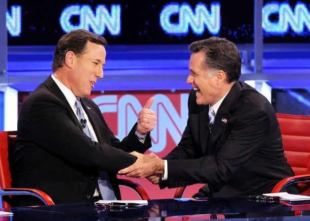 Santorum holds his thumb up, while Romney grabs his arm and grins