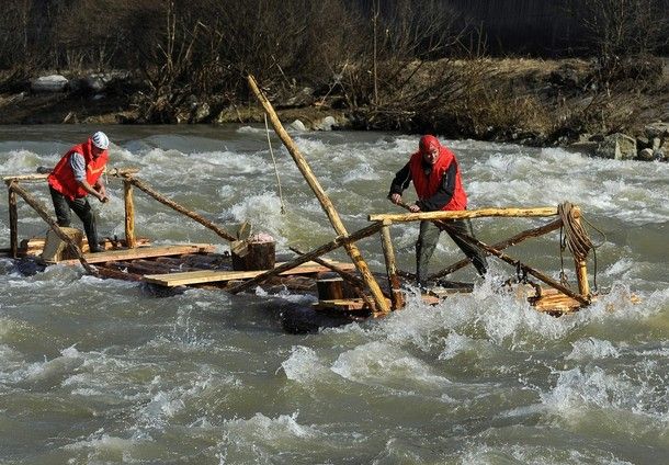 image of two white men rafting on a wooden raft down a river