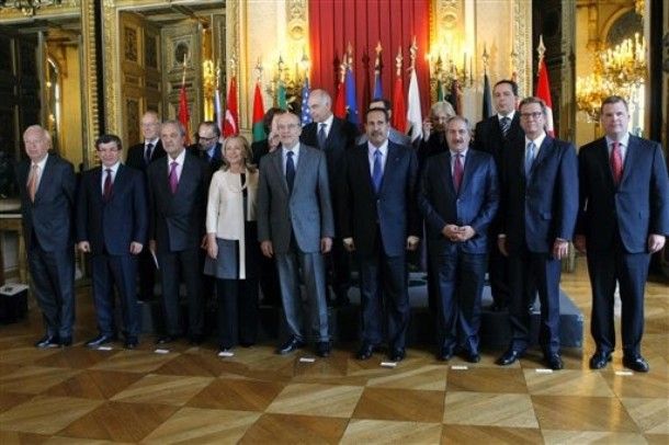 Hillary Clinton stands with a group of men, all wearing dark suits