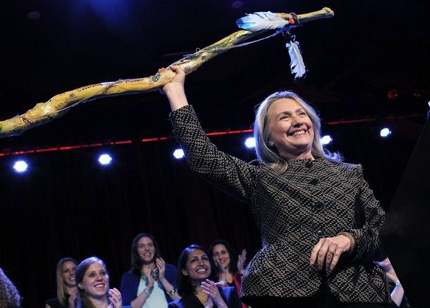 image of Hillary Clinton holding the New York Women's Foundation Century Award, which looks like a bow, over her head