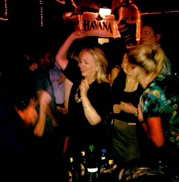 image of Hillary Clinton dancing in a club with her arms in the air, grinning