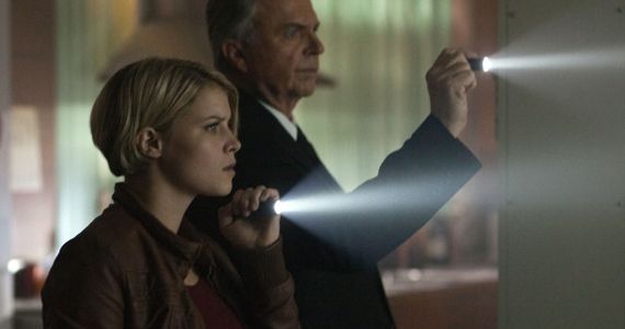 image of Sarah Jones and Sam Neill investigating a dark space with flashlights