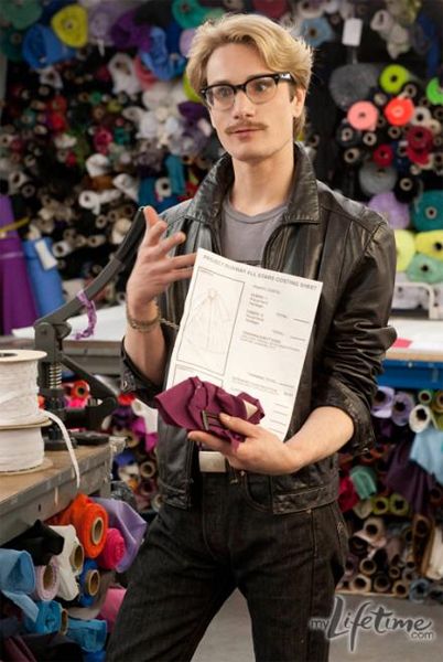 designer Austin Scarlett stands in a fabric shop, holding his design and some fabric