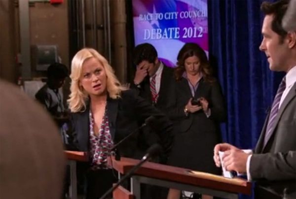 image of Leslie Knope at a podium giving an incredulous look to Bobby Newport, also at a podium, during a debate