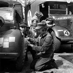 image of a very young Queen Elizabeth II changing a truck tire in uniform during WWII